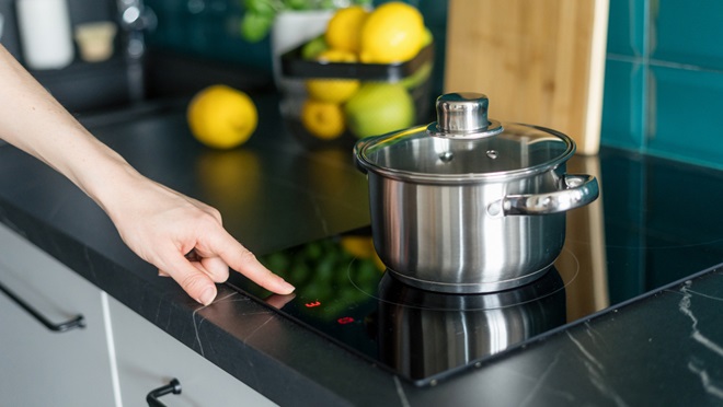 turning on an induction cooktop with a saucepan